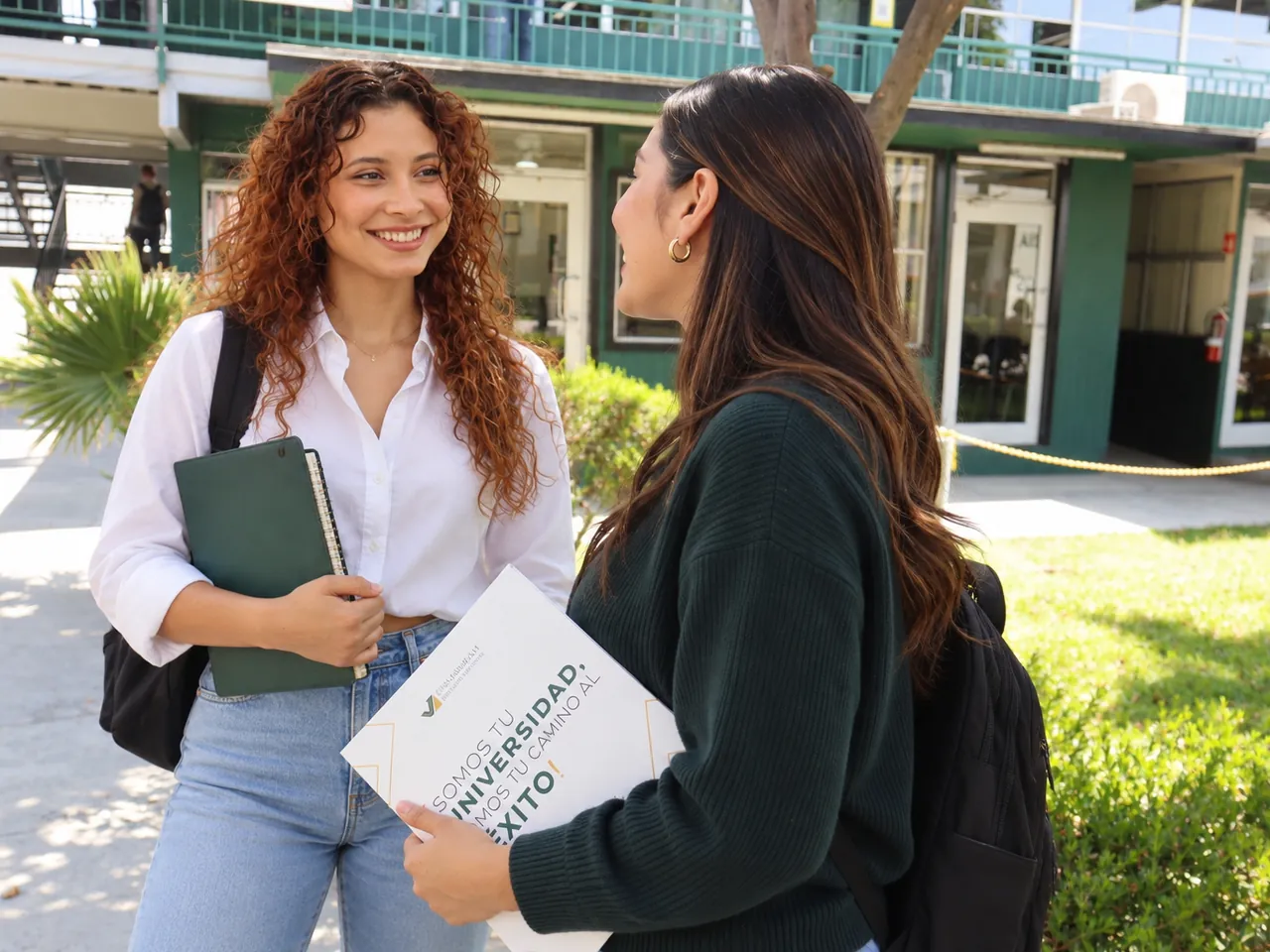 Dos alumnas conversando en el campus con sus cuadernos